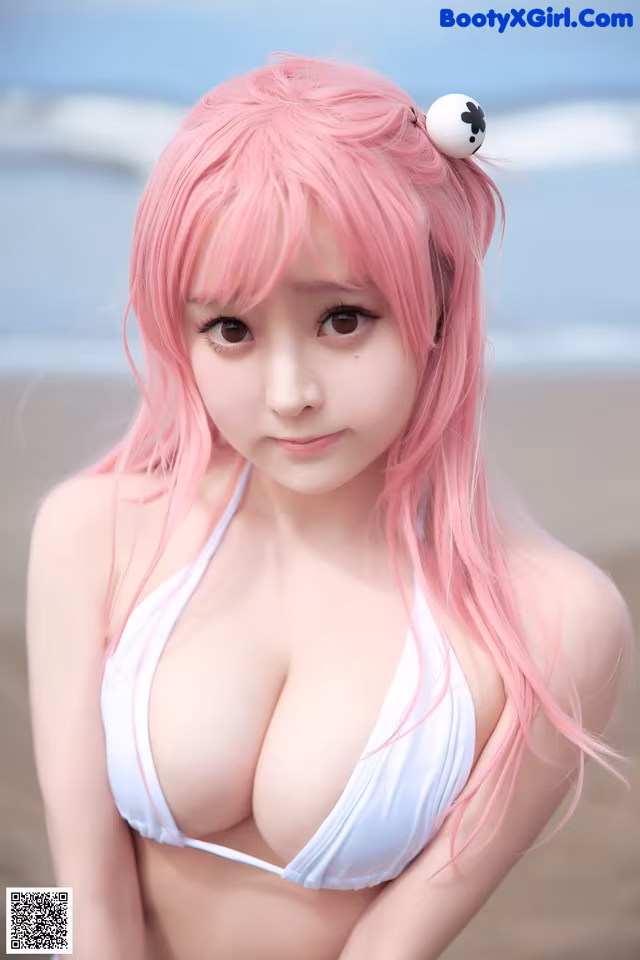 A woman with pink hair wearing a white bikini on the beach.