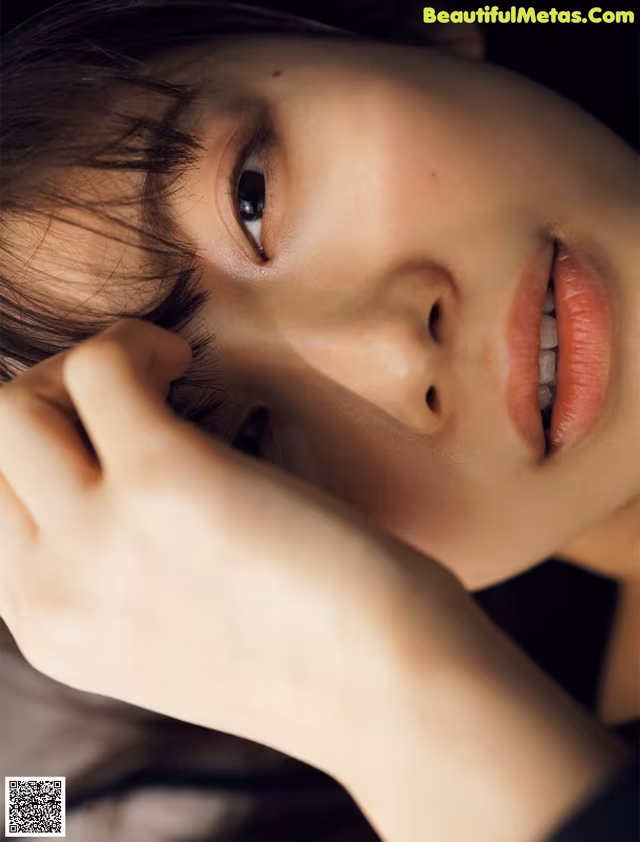 A close up of a woman's face with her hand on her chin.