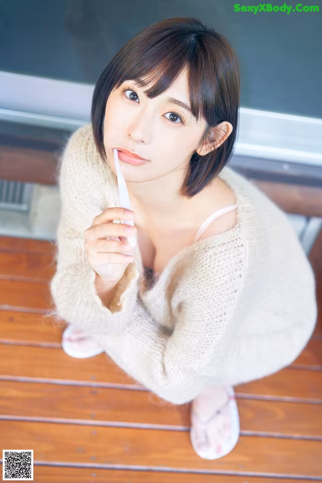 A woman sitting on a wooden floor holding a toothbrush.