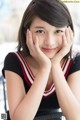 A young woman sitting at a table with her hands on her face.