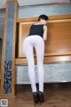 A woman in white leggings and high heels posing for the camera.