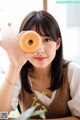 A woman holding a donut in front of her face.