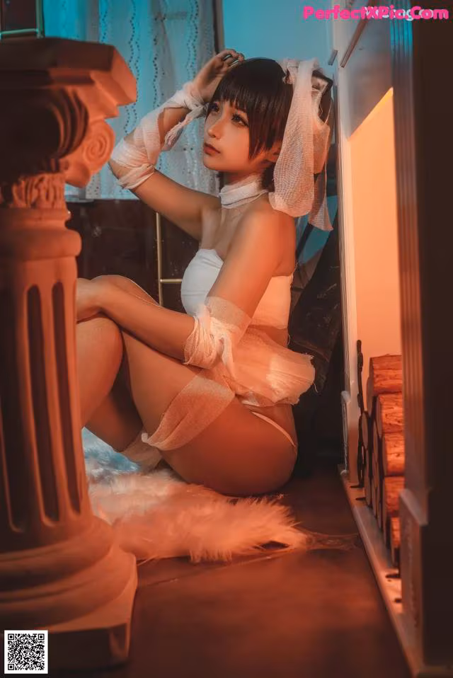 A woman in a white lingerie sitting on the floor.