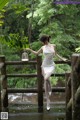 A woman in a white dress standing on a wooden bridge.