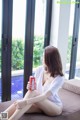 A woman sitting on a couch holding a can of soda.