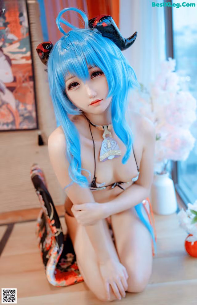 A woman with blue hair sitting on the floor.