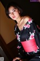 A woman in a black and pink kimono posing for a picture.