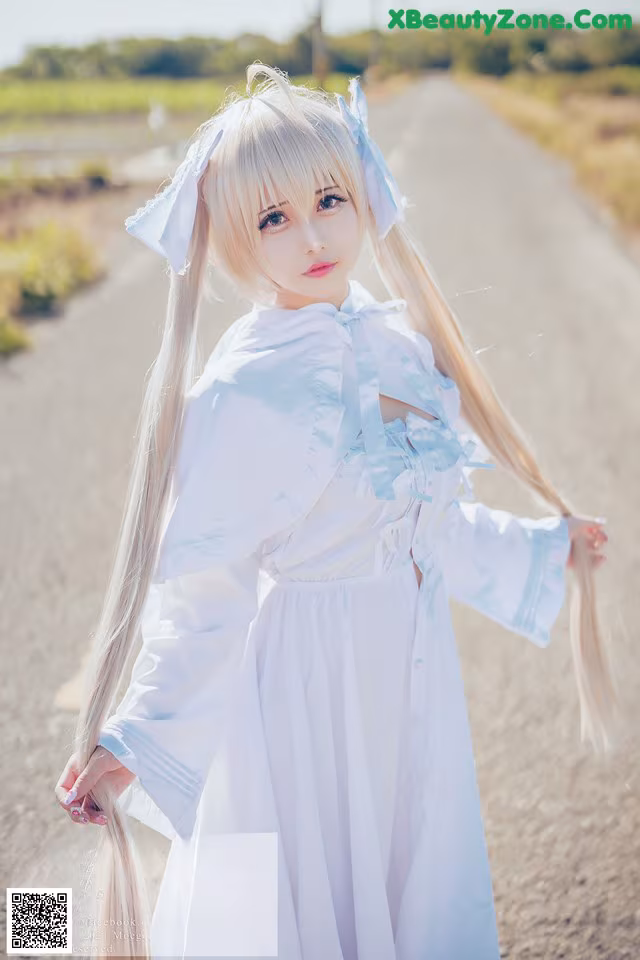 A woman in a white dress standing on a dirt road.