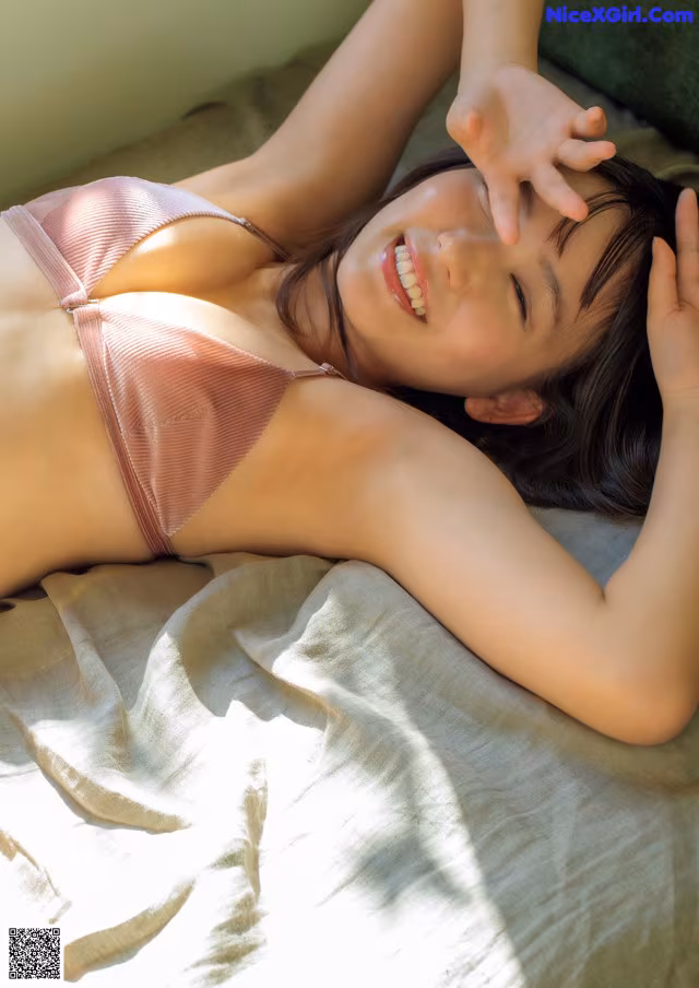 A woman laying on a bed in a pink bikini.