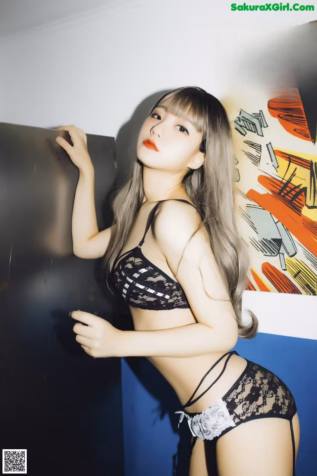 A woman in a black lingerie leaning against a wall.