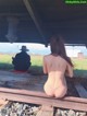 A naked woman sitting on a train track next to a man.