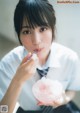 A woman in a school uniform eating a bowl of ice cream.