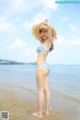 A woman in a blue and white bikini standing on a beach.